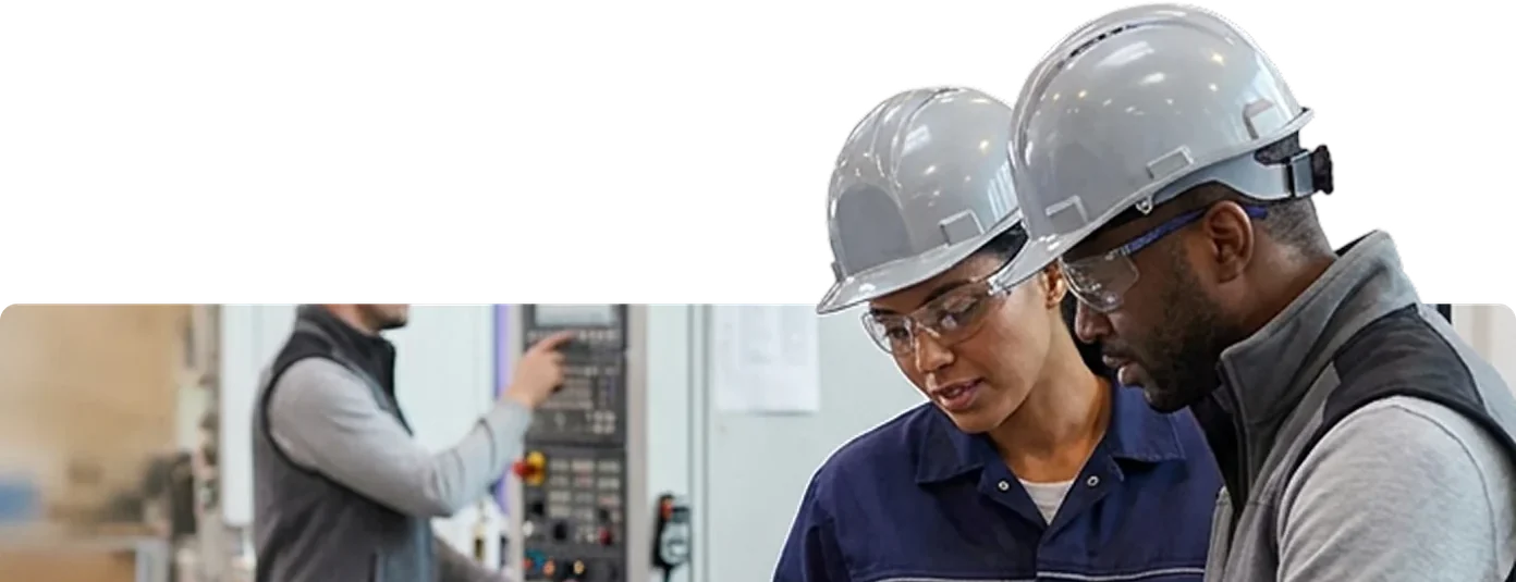 Two technicians looking at a chart on a tablet at a workbench